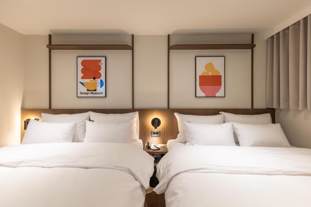 two beds in a hotel room with white sheets at Vinetree Boutique Hotel in Seoul