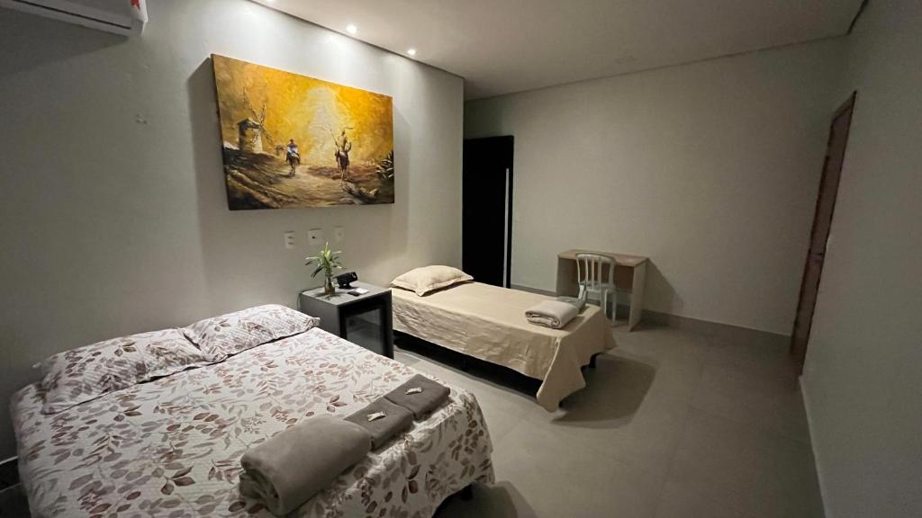 een slaapkamer met twee bedden en een schilderij aan de muur bij Casa Cobogó - 5min da Granja e da ANP in Brasilia