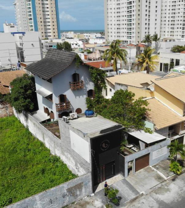 a small white house in a city with buildings at Enjoy suítes in Aracaju