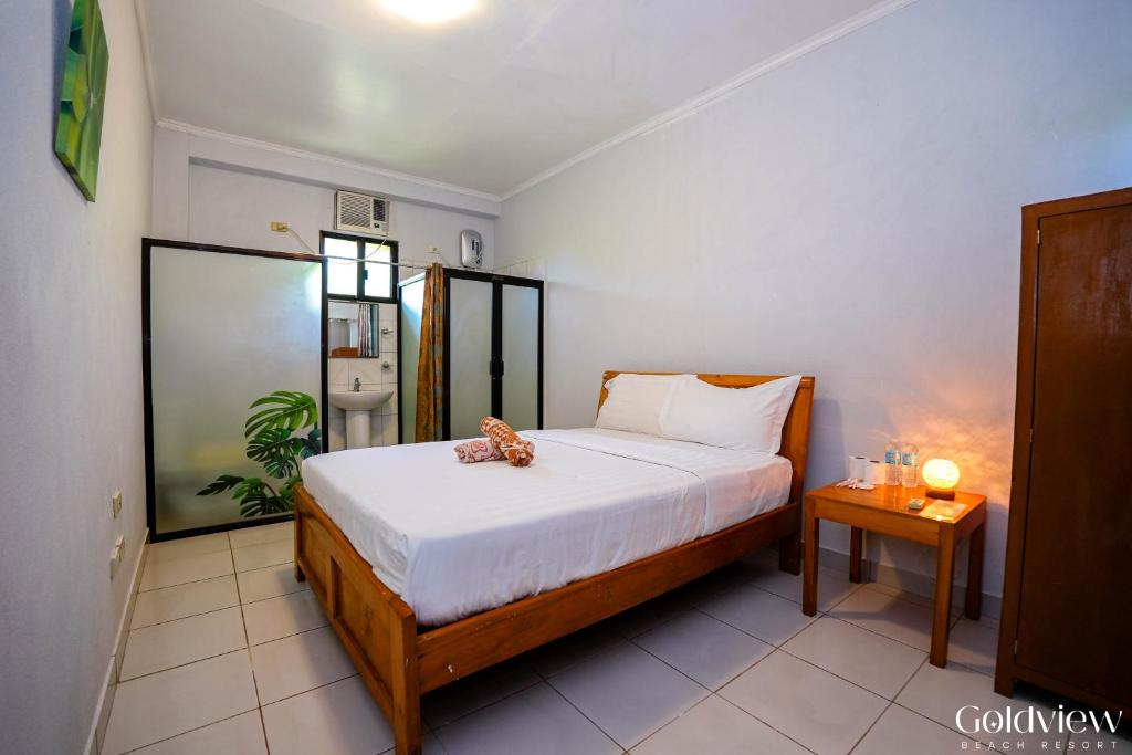 een slaapkamer met een bed met een knuffeldier erop bij Gold View Beachfront Resort in Timbaon
