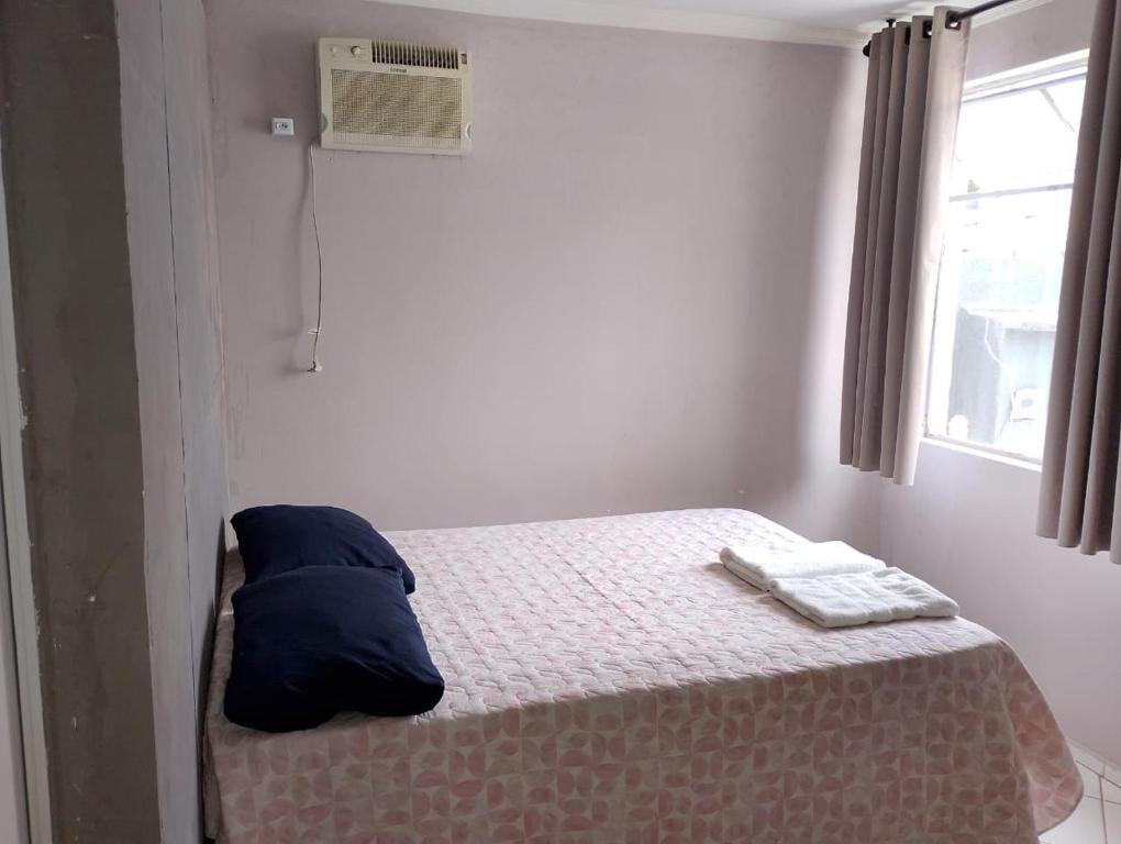 een slaapkamer met een bed met een blauw kussen en een raam bij Pousada Utopia in Aparecida