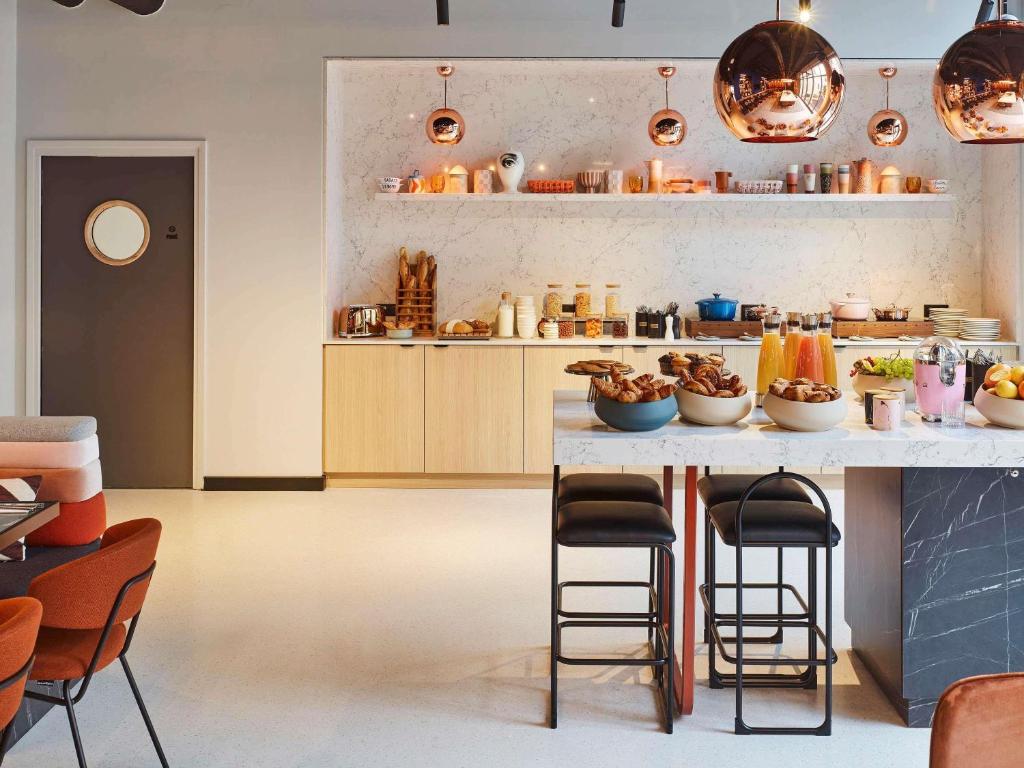 eine Küche mit einer Theke mit Stühlen und einem Tisch in der Unterkunft Tribe Paris Saint Ouen in Saint-Ouen