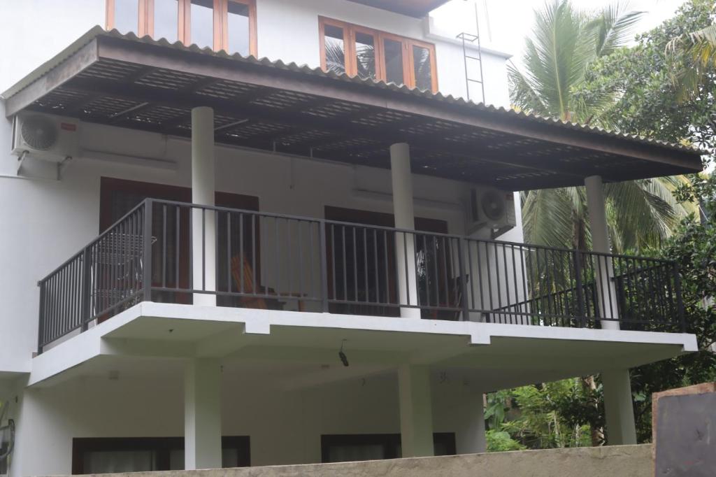 a white house with a balcony on it at Villa Pilseli in Unawatuna