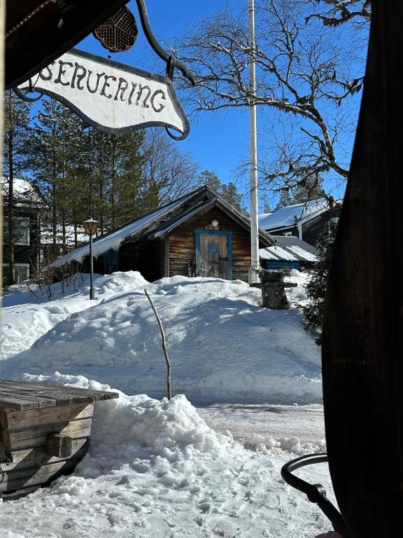 a snow covered yard with a sign in front of a building at Lillstugan in Sälen