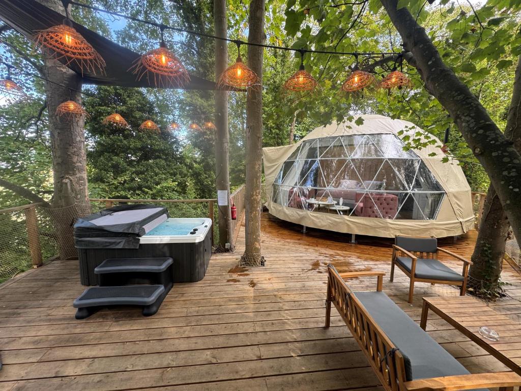 a tent on a deck with a grill and a table and chairs at Bulle au Fil de l'eau in Romilly-sur-Andelle