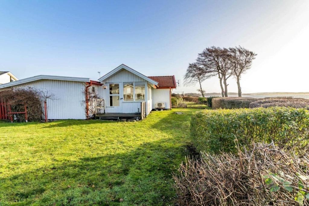 a small white house in a grassy field at BLE885-Ramdala-Ormen-langes-vaeg-10 in Ramdala