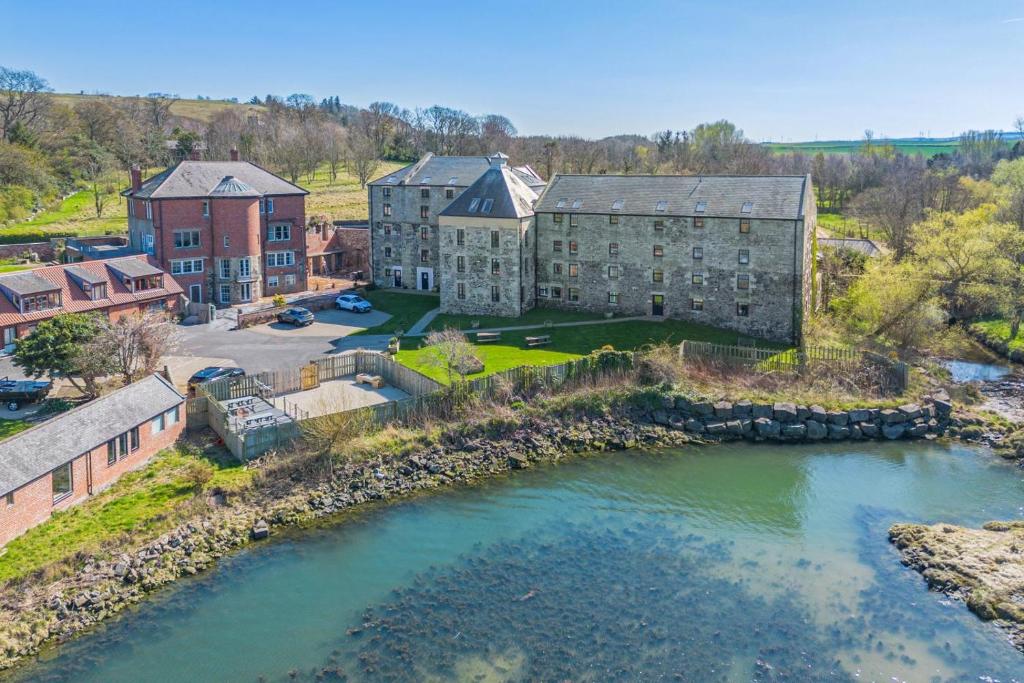 an aerial view of a building next to a river at 3 Bed in Waren Mill oc-gd1928 in Bamburgh