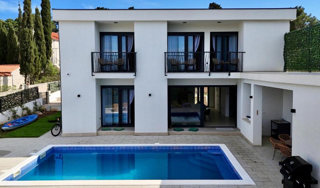 a villa with a swimming pool in front of a house at White Villa, Brac in Splitska