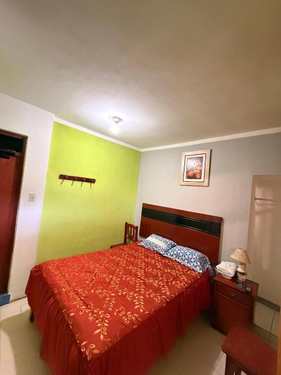 una camera con un letto rosso e una parete verde di HOSTAL GRAU a Churín