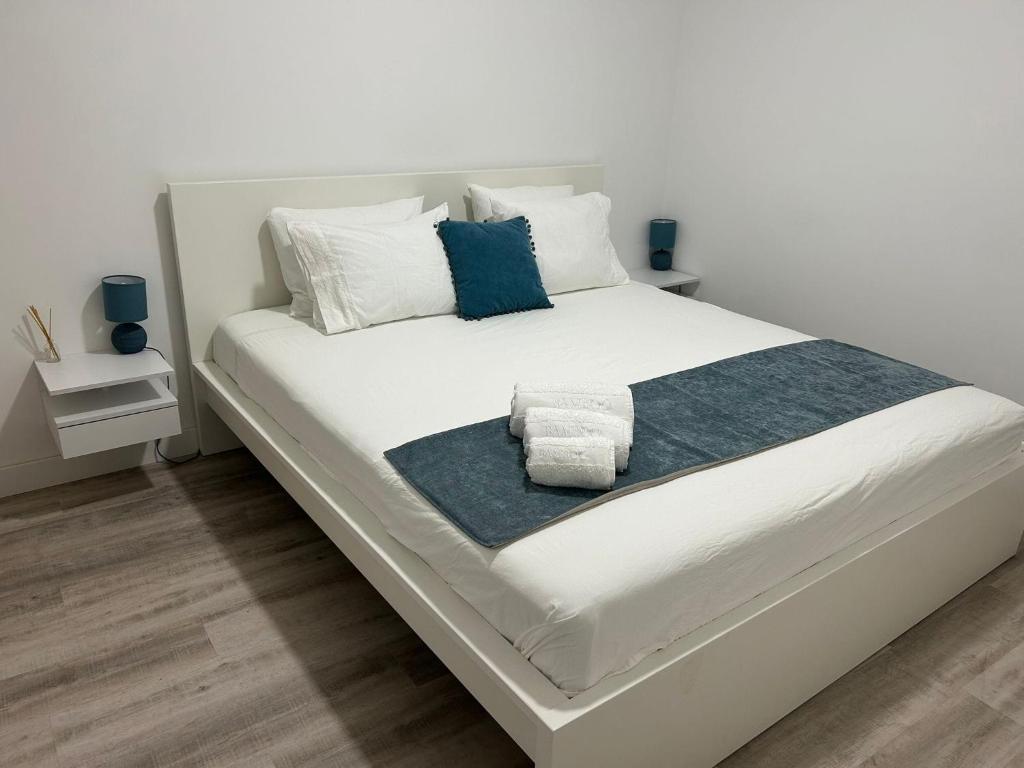 een wit bed met blauwe en witte kussens erop bij Casa Rosa in Parede