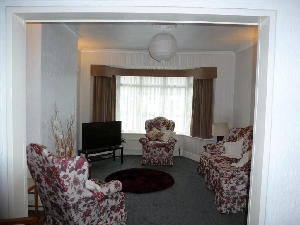a living room with two chairs and a television at Beautiful 'Rose-Dene' with ample parking in Sheerness