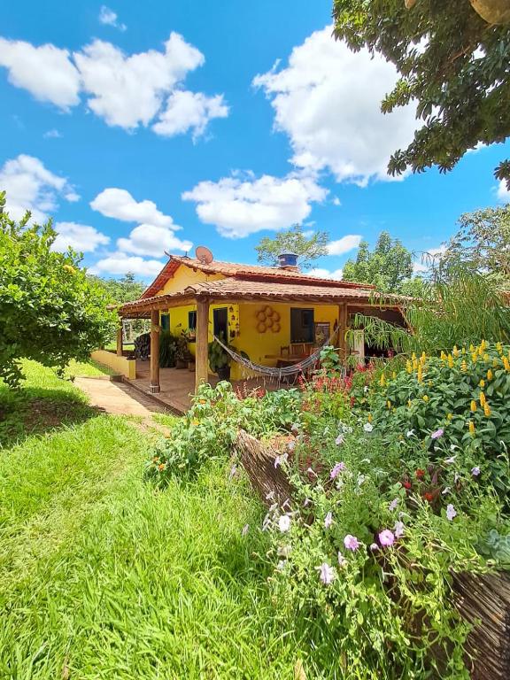 a yellow house in a garden with flowers at Recanto das Aves in Botumirim