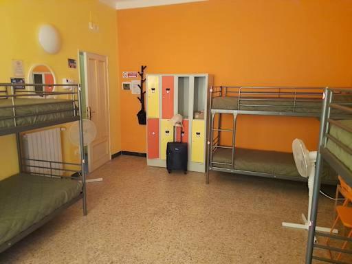 a room with three bunk beds and an orange wall at pisa train station hostel in Pisa