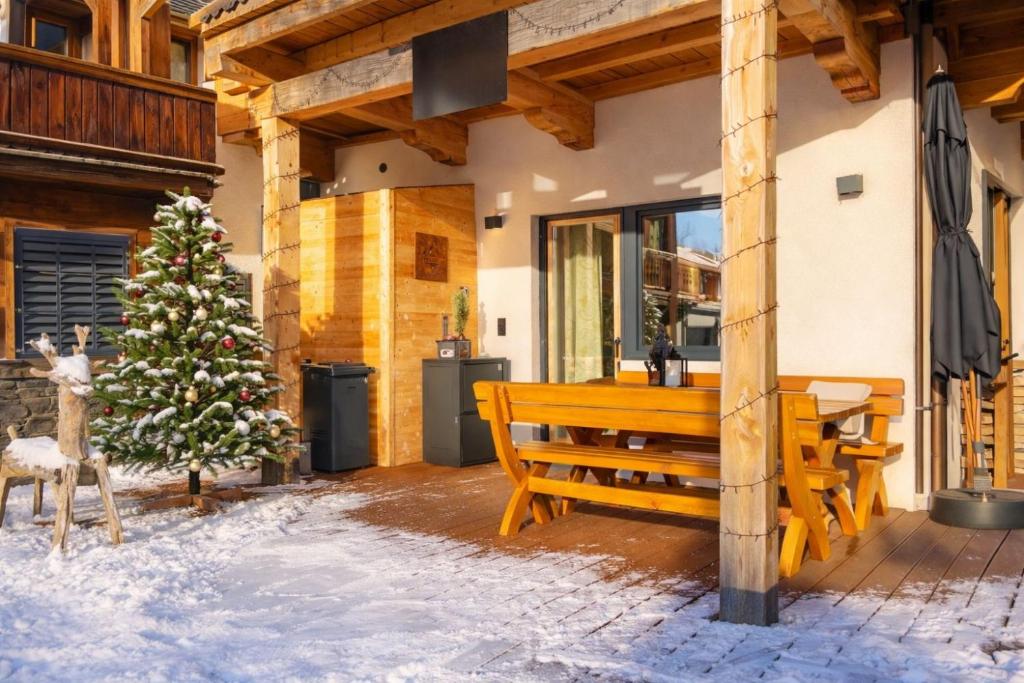 una panchina di legno seduta fuori da una casa con un albero di Natale di GondelApart Ski in Ski out a Jochberg
