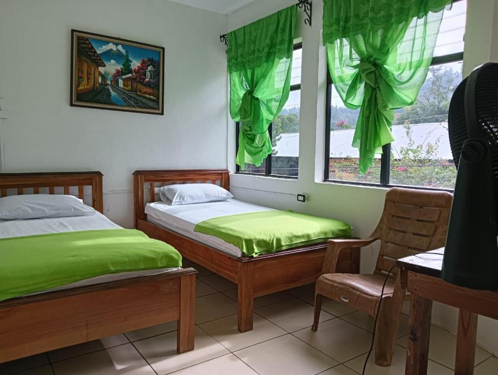 twee bedden in een kamer met groene gordijnen bij Hotel Rabin Itzam in Lanquín