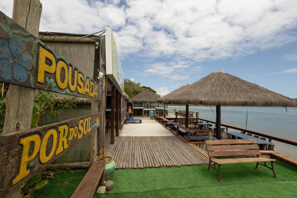 a resort with a dock with benches and a table at Pousada Pôr Do Sol - Ilha do Mel - Nova Brasília in Paranaguá