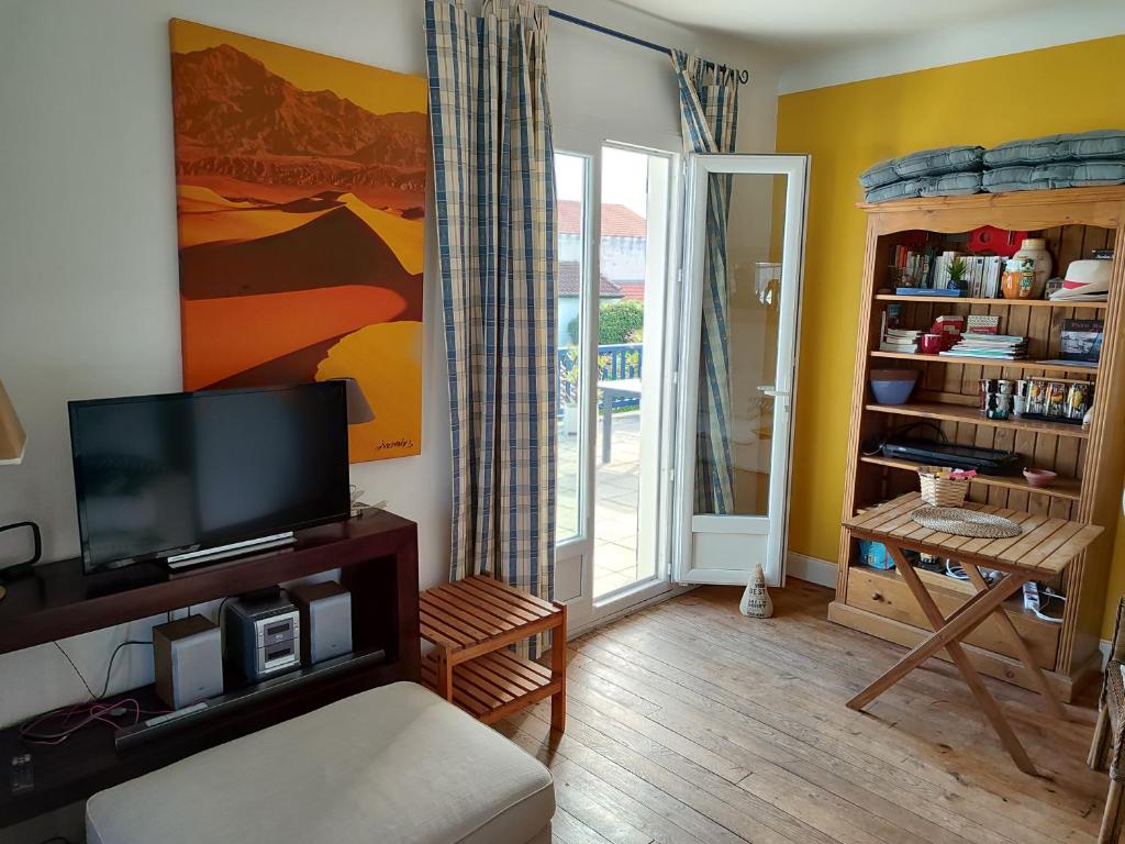 a living room with a flat screen tv next to a door at Appartement avec Terrasse à Beaurivage in Biarritz