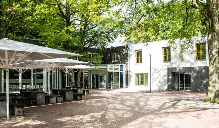 een gebouw met tafels en parasols op een binnenplaats bij Wilhelm Kliewer Haus in Mönchengladbach