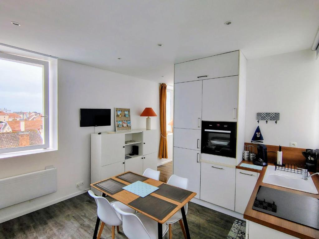 een keuken met een tafel en een keuken met witte kasten bij escapade à Wimereux in Wimereux