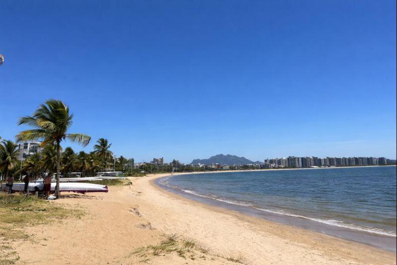 a sandy beach with palm trees and the ocean at Flat Blue Praia de Camburi in Vitória