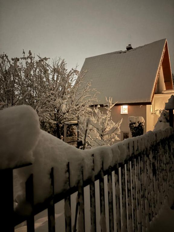 a fence covered in snow next to a house at Dom Na Wzgórzu in Poręba