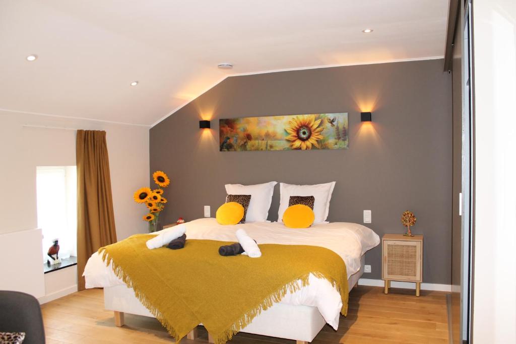 una camera da letto con un letto grande con cuscini gialli di Le Relais de Lou maison d'hôtes 