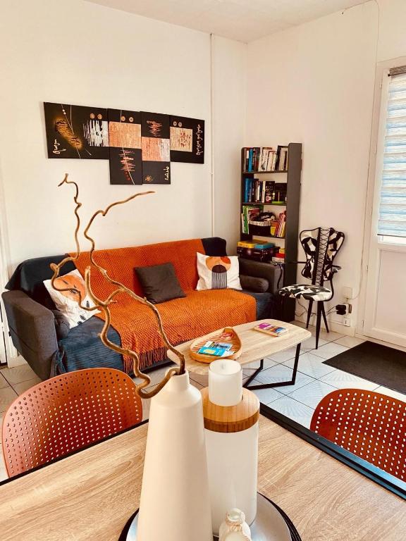 a living room with an orange couch and a table at Maison idéale pour visiter Bordeaux in Ambarès-et-Lagrave
