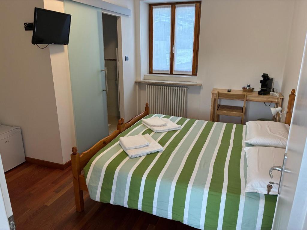 een slaapkamer met een bed met groene en witte gestreepte lakens bij Affittacamere Penasa in Rabbi