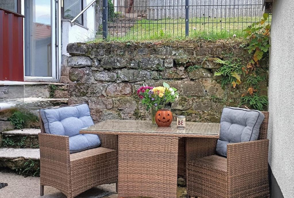 a table with two chairs and a vase of flowers at Ferienwohnung Urlaubszeit in Illingen
