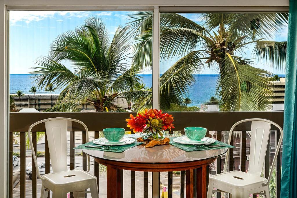 a table with a view of the ocean and palm trees at Kona Mansions#301 in Kailua-Kona
