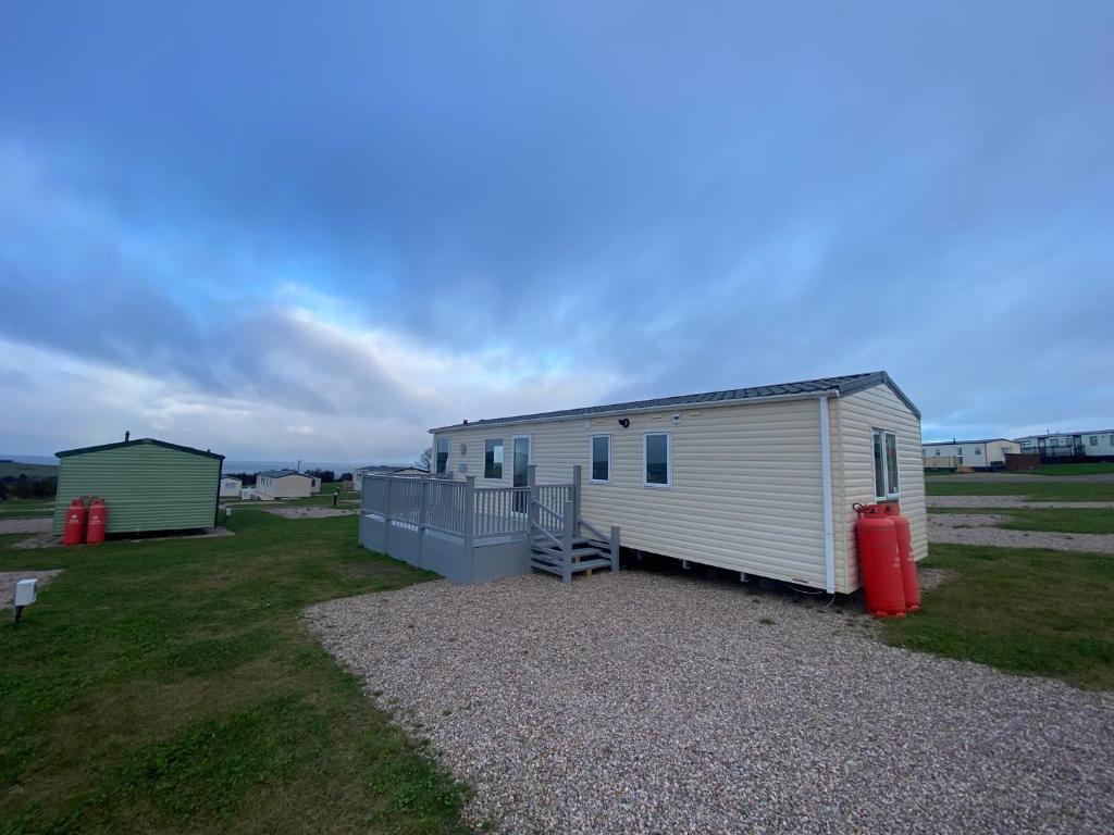 a small white shed with a red container in a field at No 56 Headiton Caravan Park in Banff