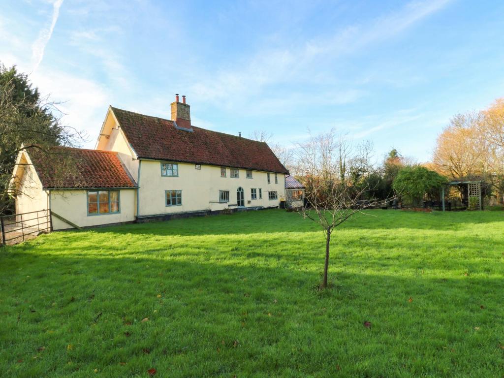 a white house with a tree in a field at Town Farm in Eye