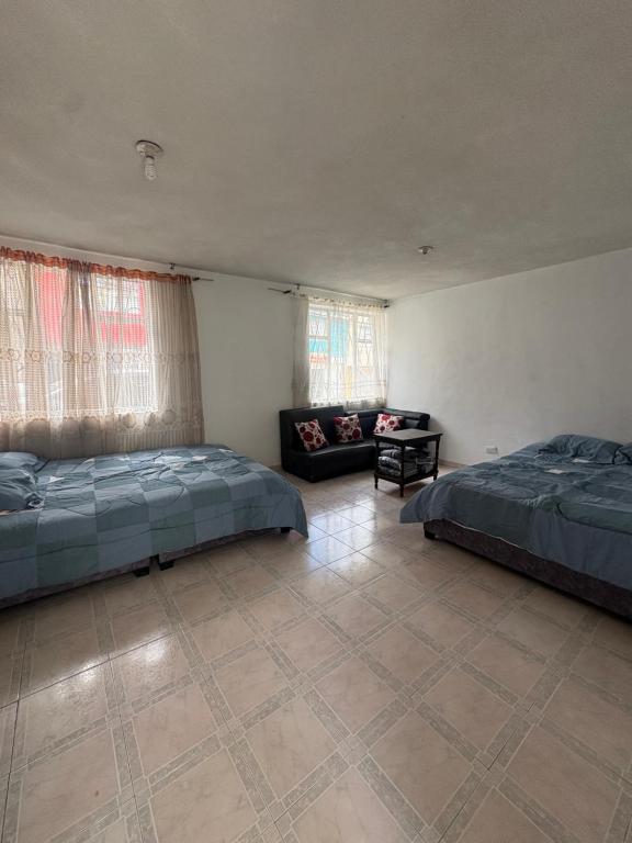 a large room with two beds and a couch at Hostal Los Robles in Pasto