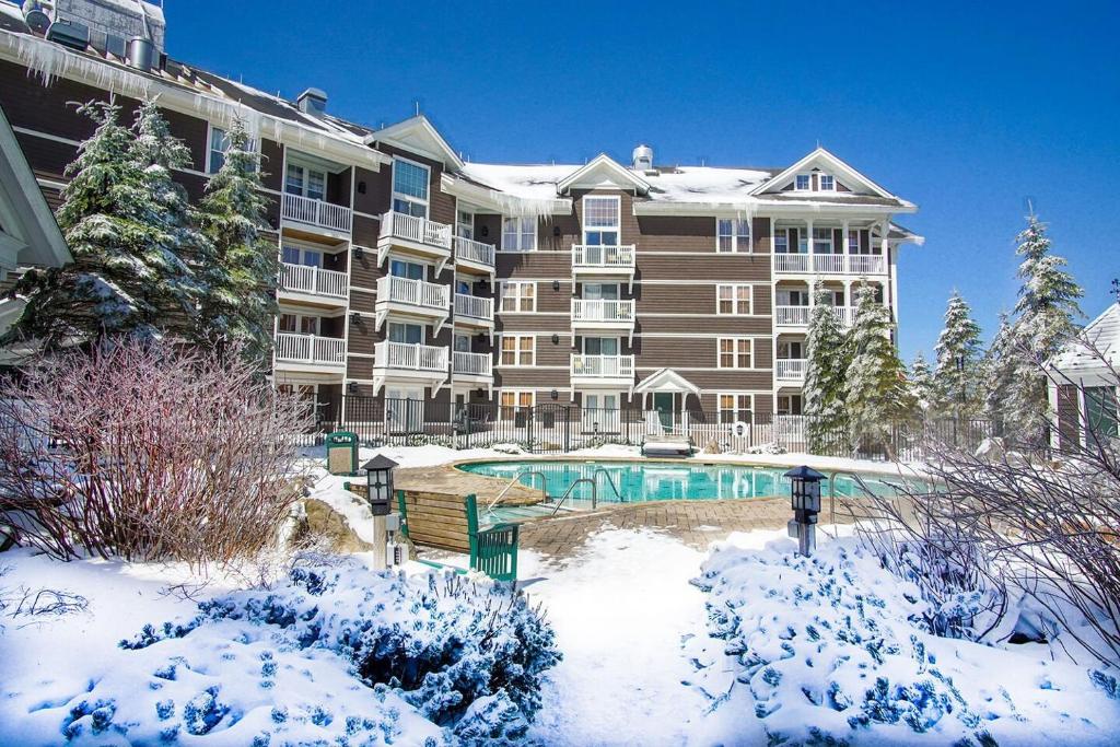 a large apartment building with a swimming pool in the snow at Allegheny Springs 414: Junior Studio Slopeside in Snowshoe