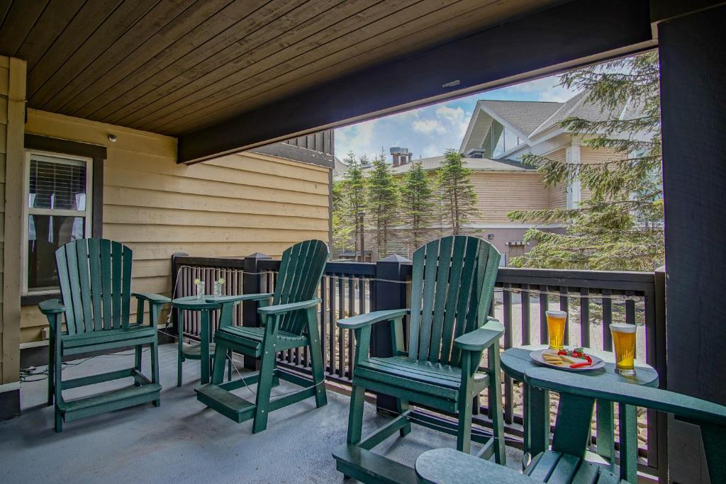 a porch with green chairs and a table with drinks at Rimfire 151- 152 Unique 2 Br Condo in Snowshoe