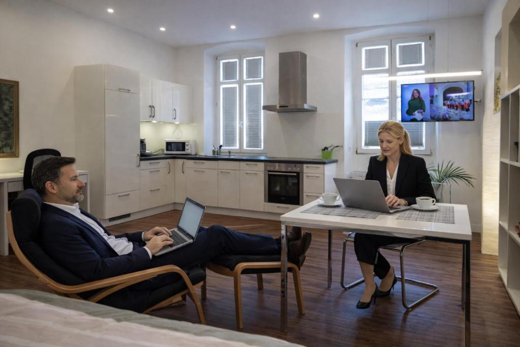 een man en een vrouw zitten aan een tafel met hun laptops bij NEWTON - für Business & längere Aufenthalte, nahe der Schweiz in Klettgau