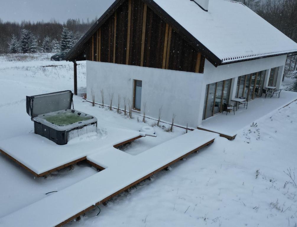 een huis bedekt met sneeuw met een bank ervoor bij Warmińska Polana - Nowy, całoroczny dom na 2 ha łące dla 8 osób - Gietrzwałd in Gietrzwałd