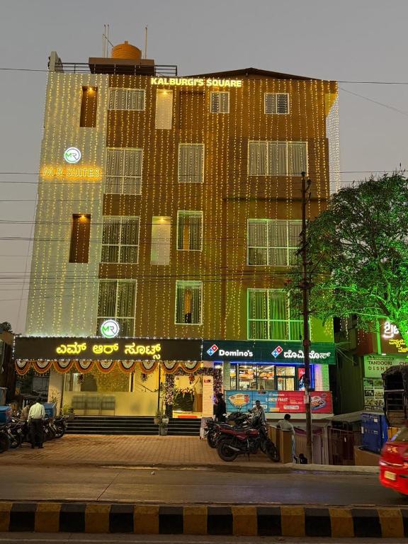 a large building with a building with a motorcycle parked in front at MR Suites Dharwad in Dhārwād