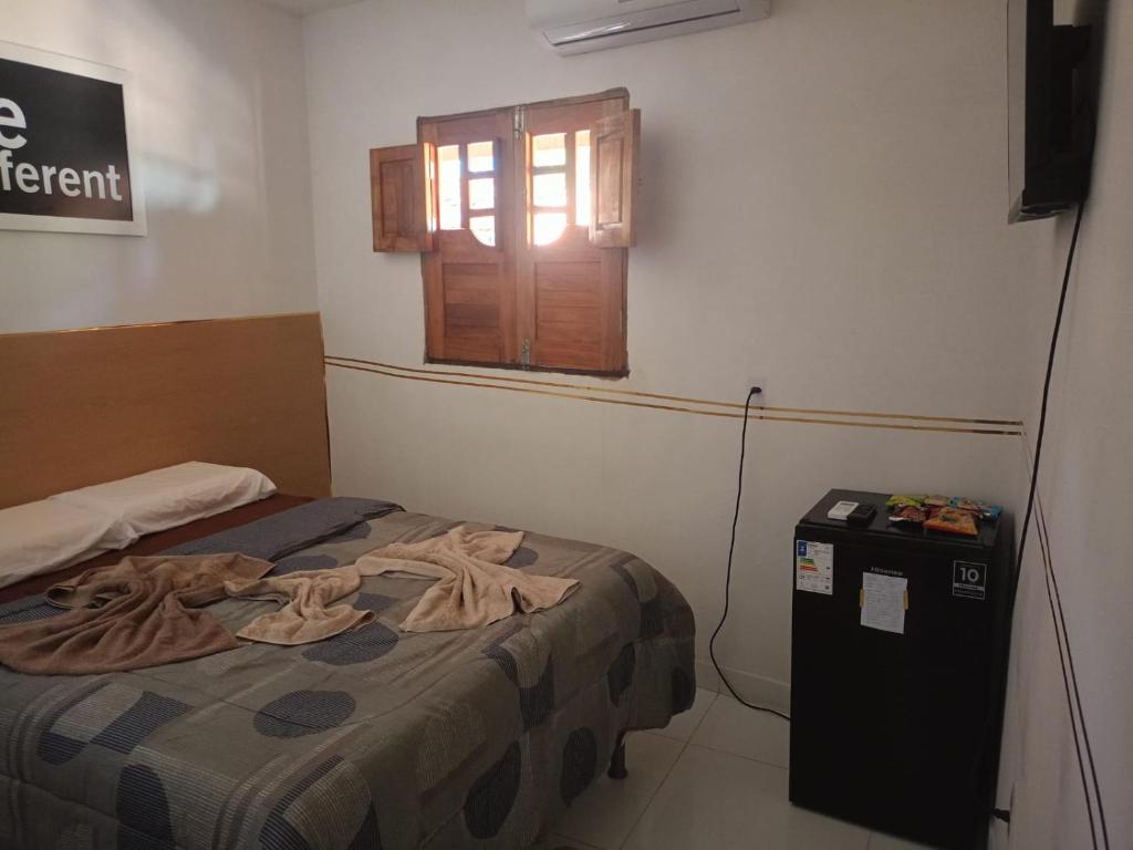 a small bedroom with a bed and a window at Pousada dos Artistas in Japaratinga