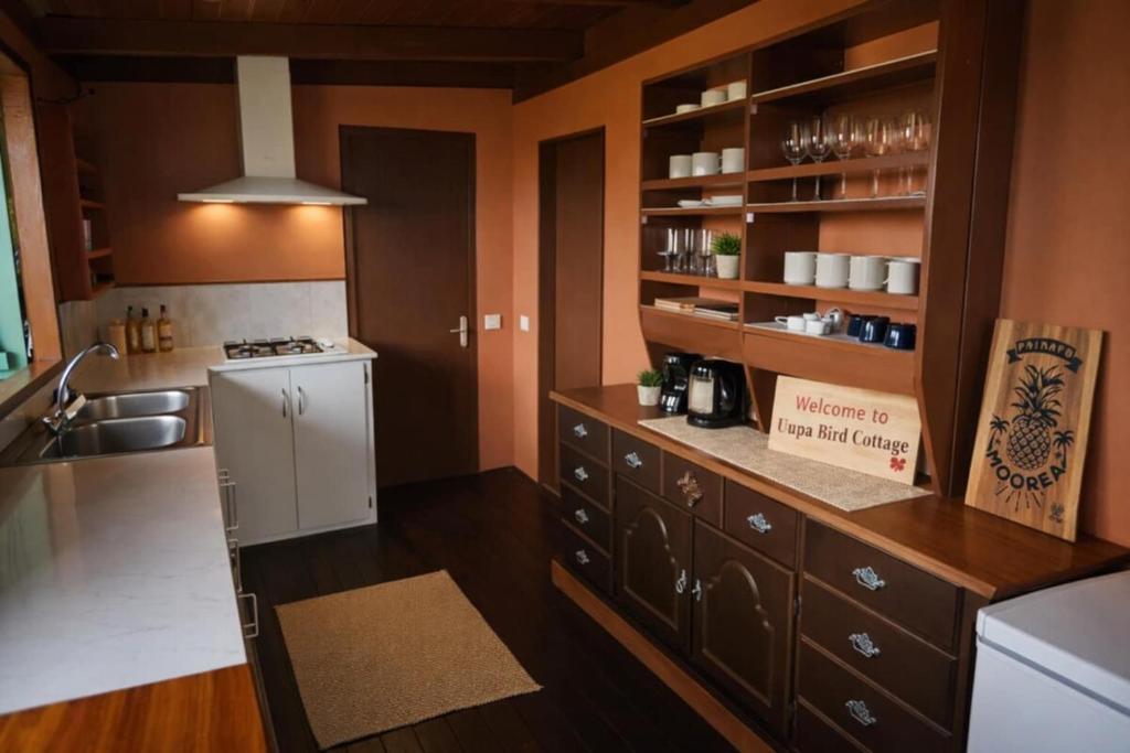 a kitchen with brown cabinets and a white refrigerator at Uupa Bird Cottage in Moorea