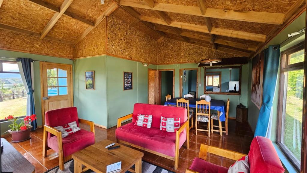een woonkamer met rode stoelen en een tafel bij Cabaña el Coirón in Cochrane