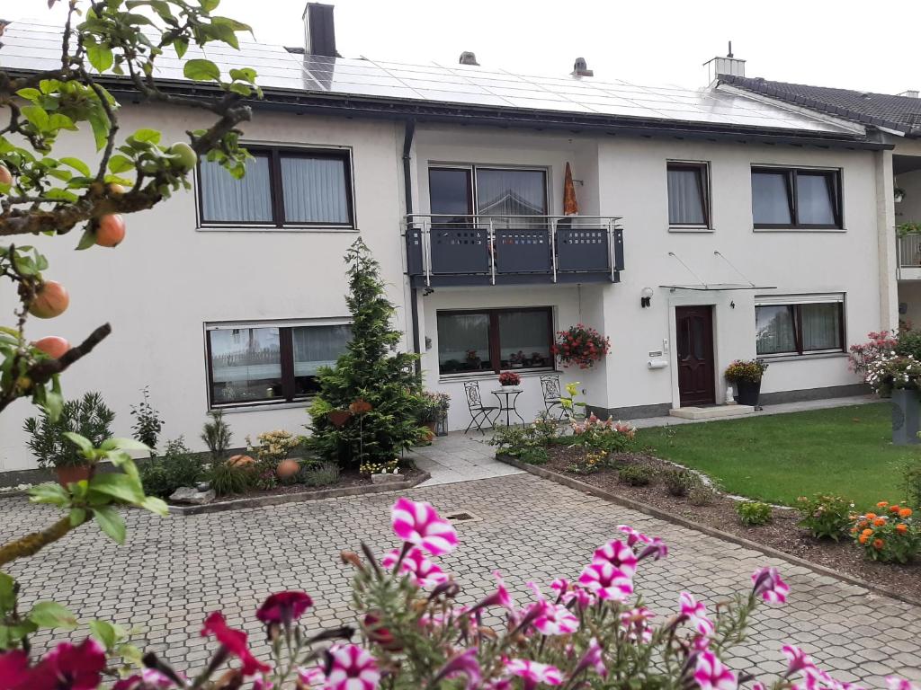 a white house with a courtyard with flowers at Ferienwohnung Schabmüller in Kelheim