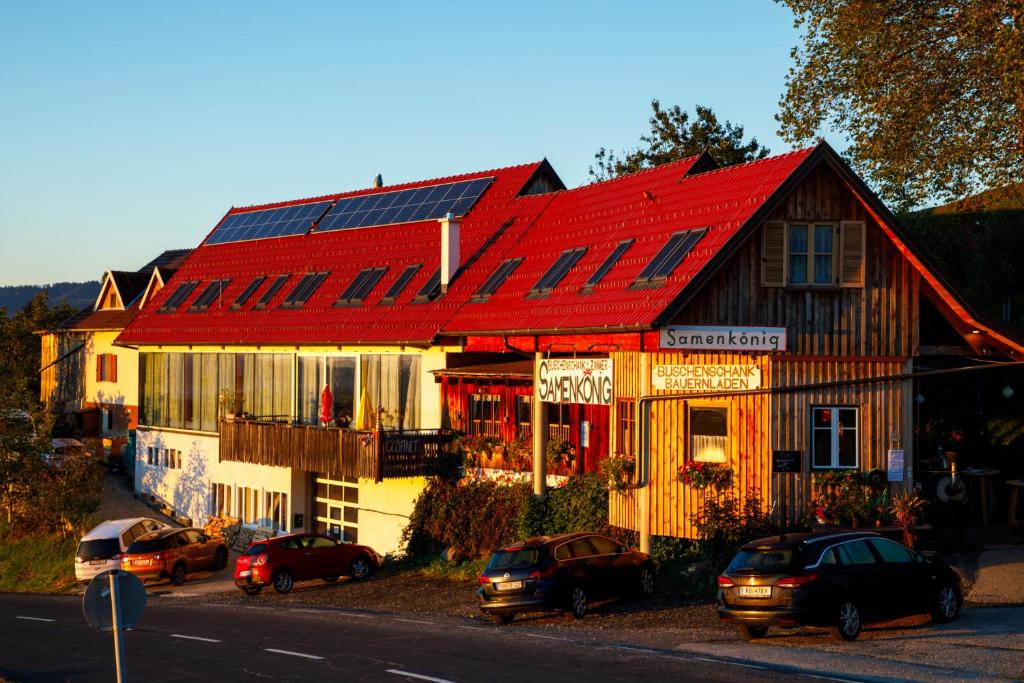 a house with a red roof with cars parked in front at Samenkönig Pschait Handels GmbH in Gamlitz