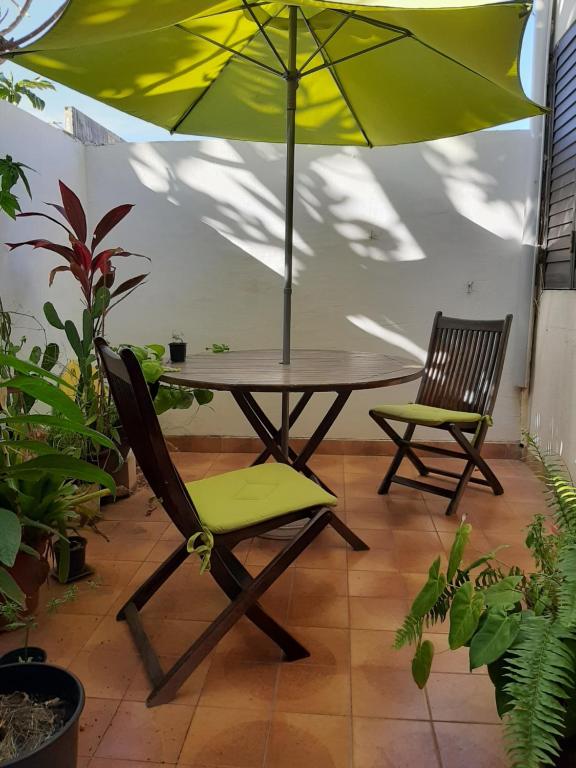 a table with an umbrella and two chairs at Comme à la maison! Le Moule in Le Moule