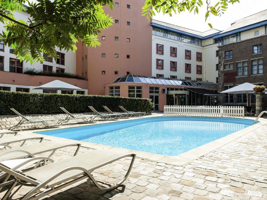 a swimming pool with lounge chairs next to a building at Novotel Gent Centrum in Ghent