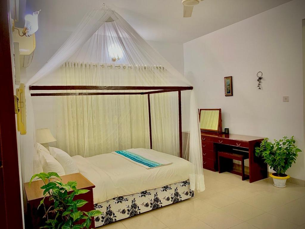 达卡Green House的一间卧室配有一张天蓬床和一张书桌