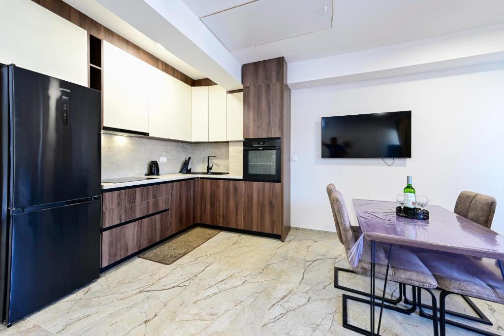 a kitchen with a table and a black refrigerator at Apartman Roso in Orebić