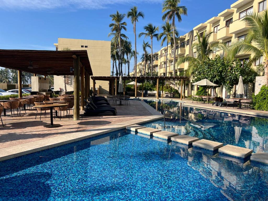 a swimming pool in front of a hotel with palm trees at Depto Moderno Oceanna frente a playa cerritos in Mazatlán
