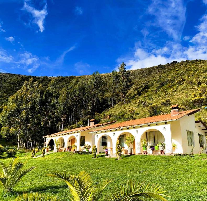 a house with a grassy yard in front of a hill at Fundo Alma Andina in Jauja
