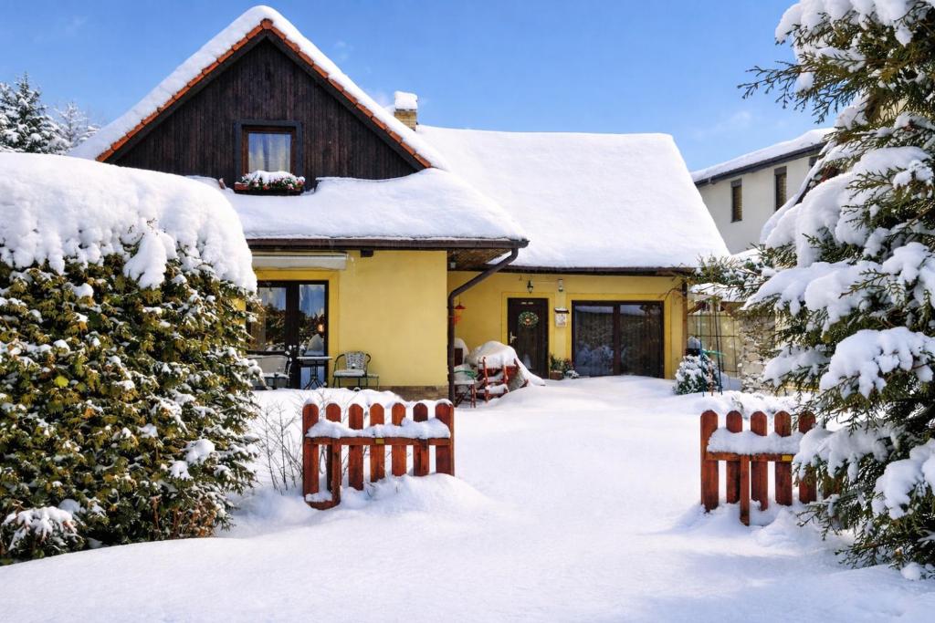 a house covered in snow with two benches at Apartmány Anička vo Važci in Važec